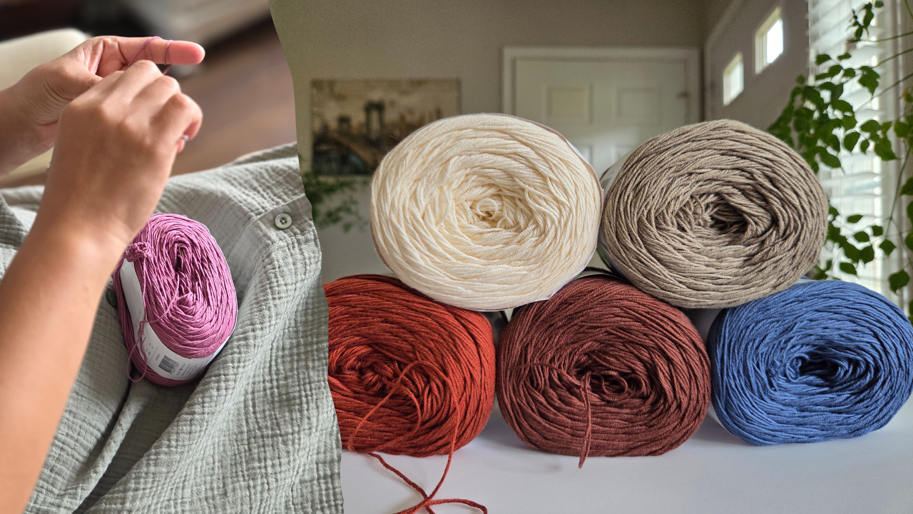 Collection of colorful yarn rolls on a table with a person's hand in the foreground crocheting.