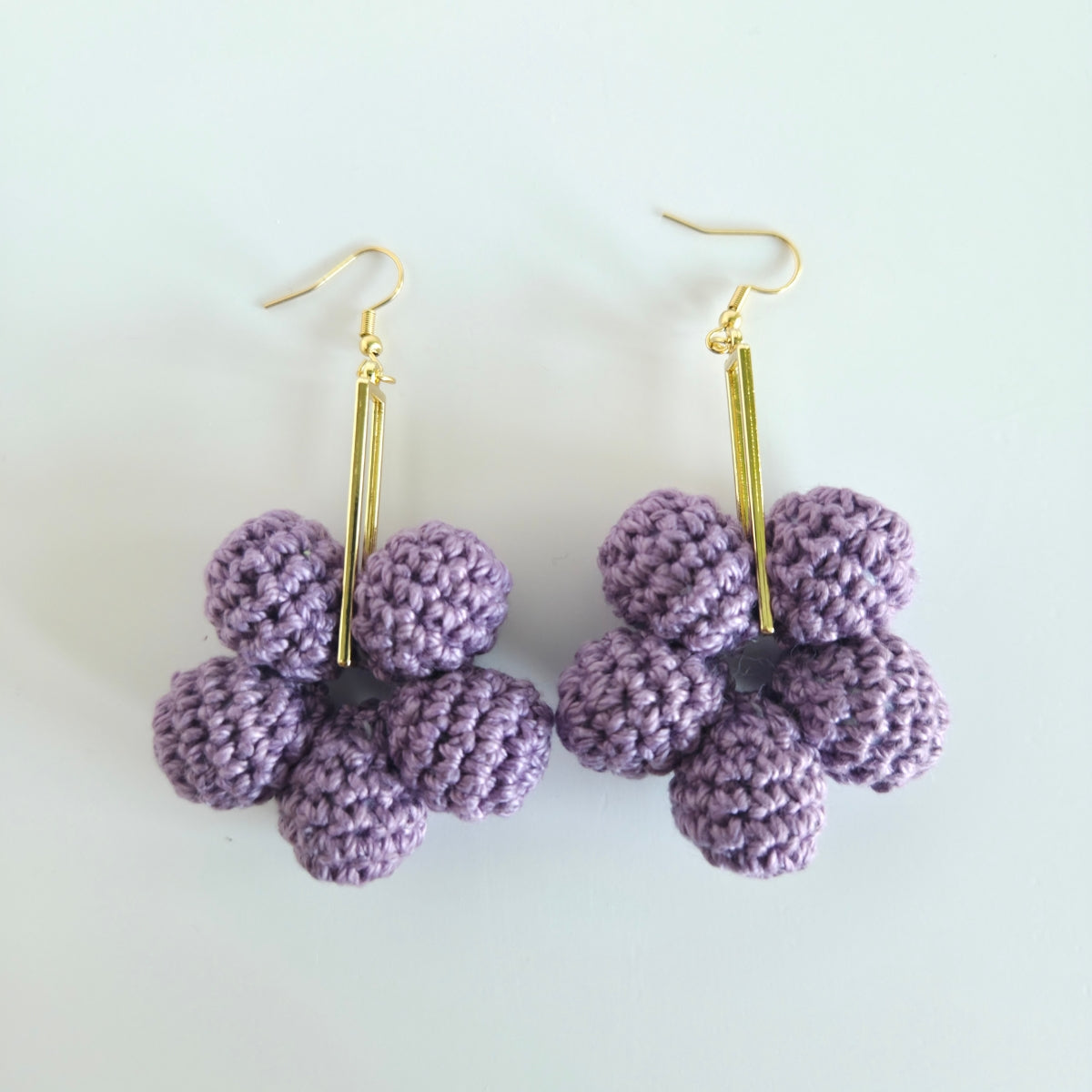 Purple flower-shaped earrings on gold hooks against a light background