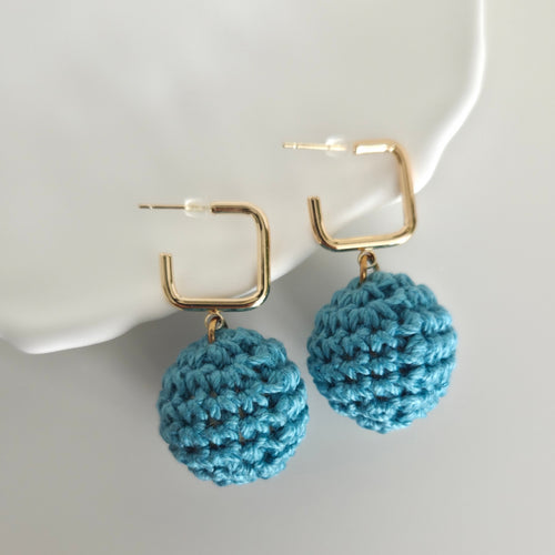 Warm teal crocheted earrings with gold hooks on a white background
