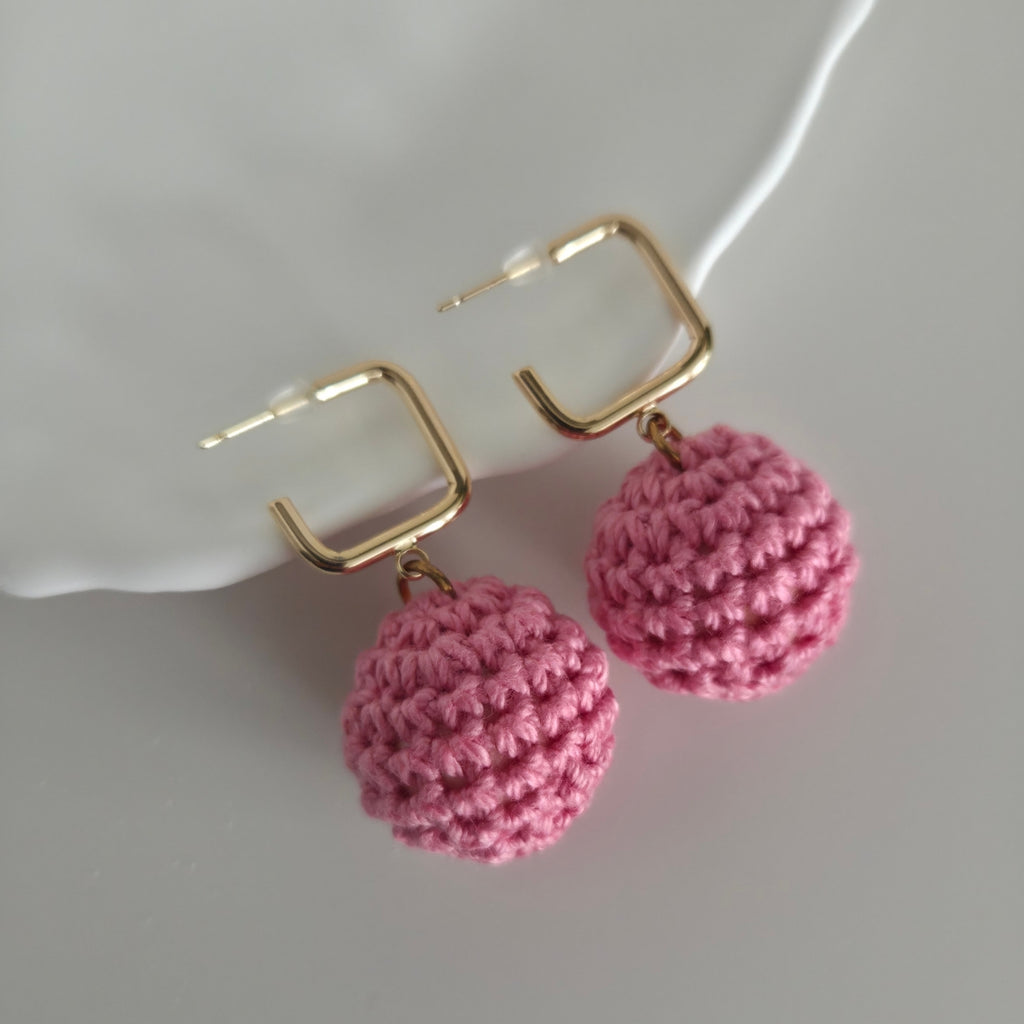 Pink crocheted earrings with gold hooks on a white background