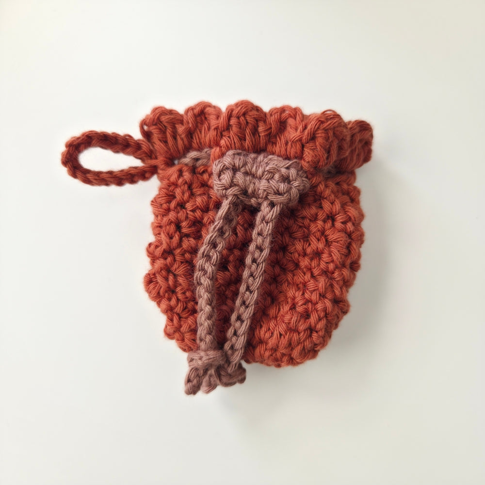 Crocheted drawstring pouch in brown red on a white background