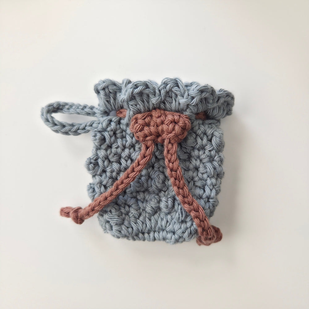 Crocheted drawstring bag with blue body and brown drawstring on a white background