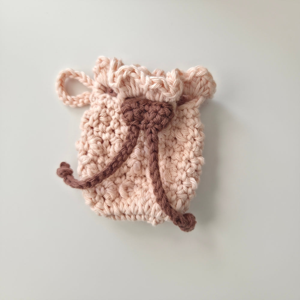 Knitted pink drawstring bag for Airpods on a light gray background