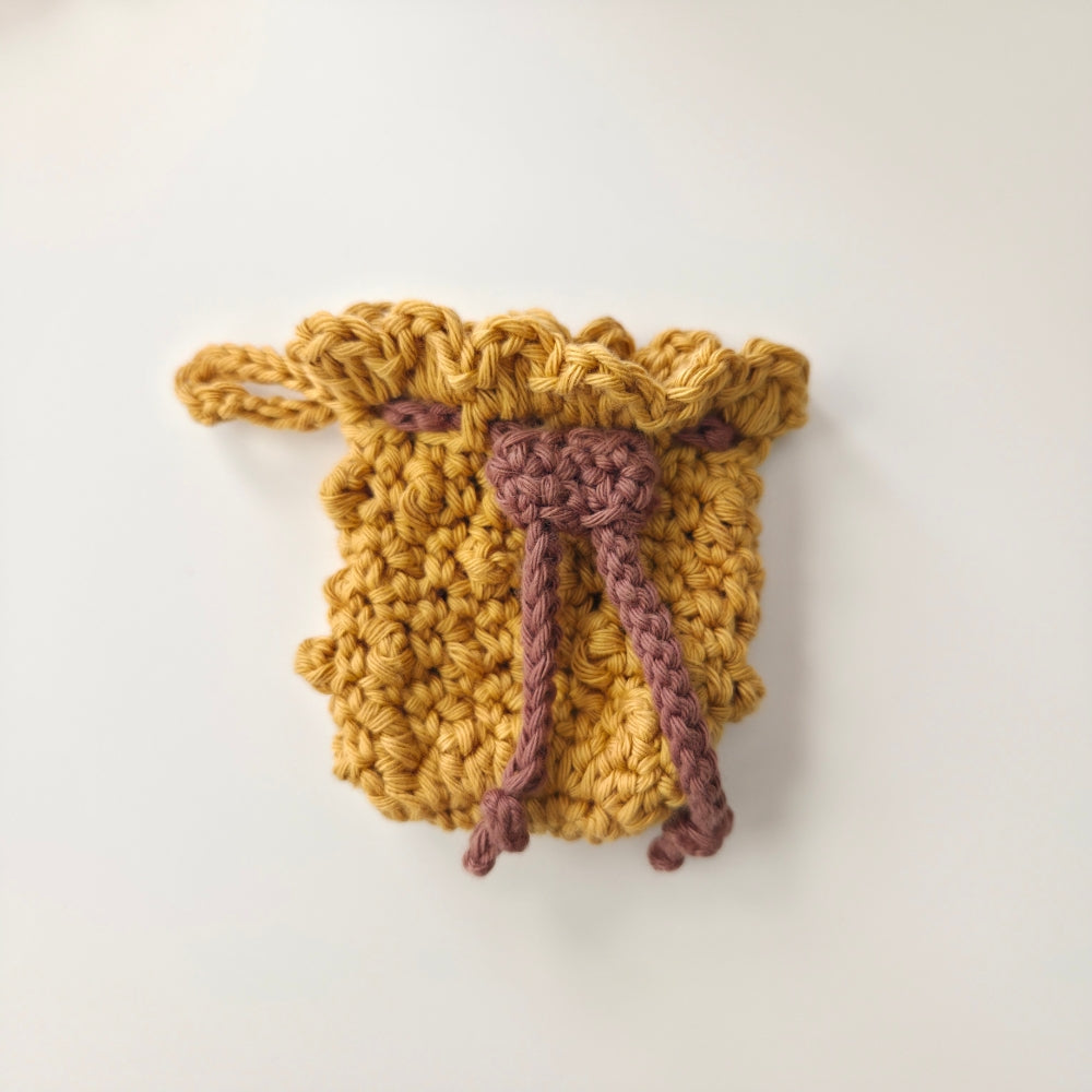Crocheted drawstring bag in honey yellow with a brown drawstring on a white background for airpods