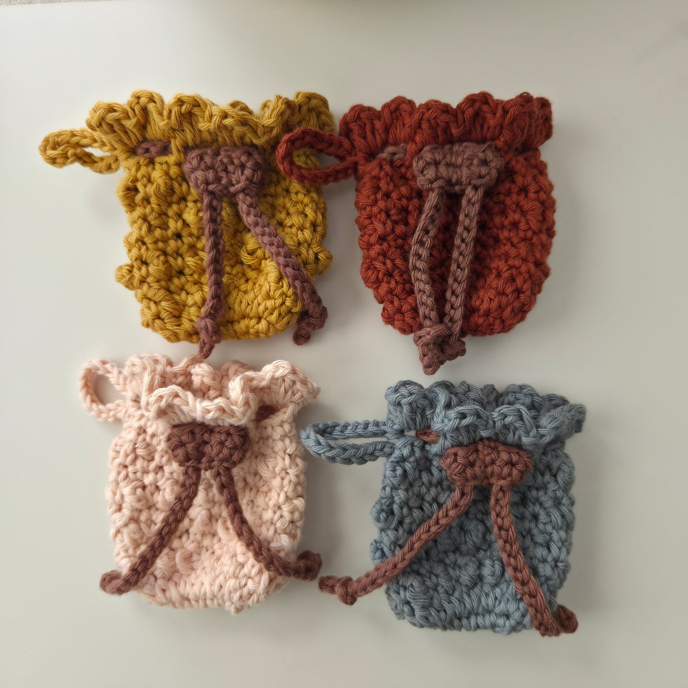 Four crocheted drawstring bags for Airpod in yellow, red, pink, and blue on a white background.
