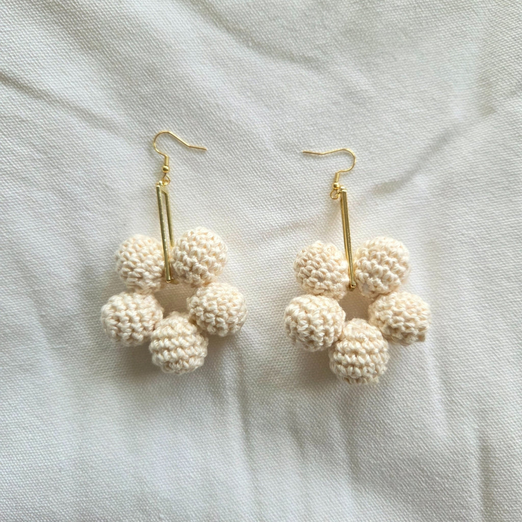 Pair of cream crochet ball earrings on a light fabric background