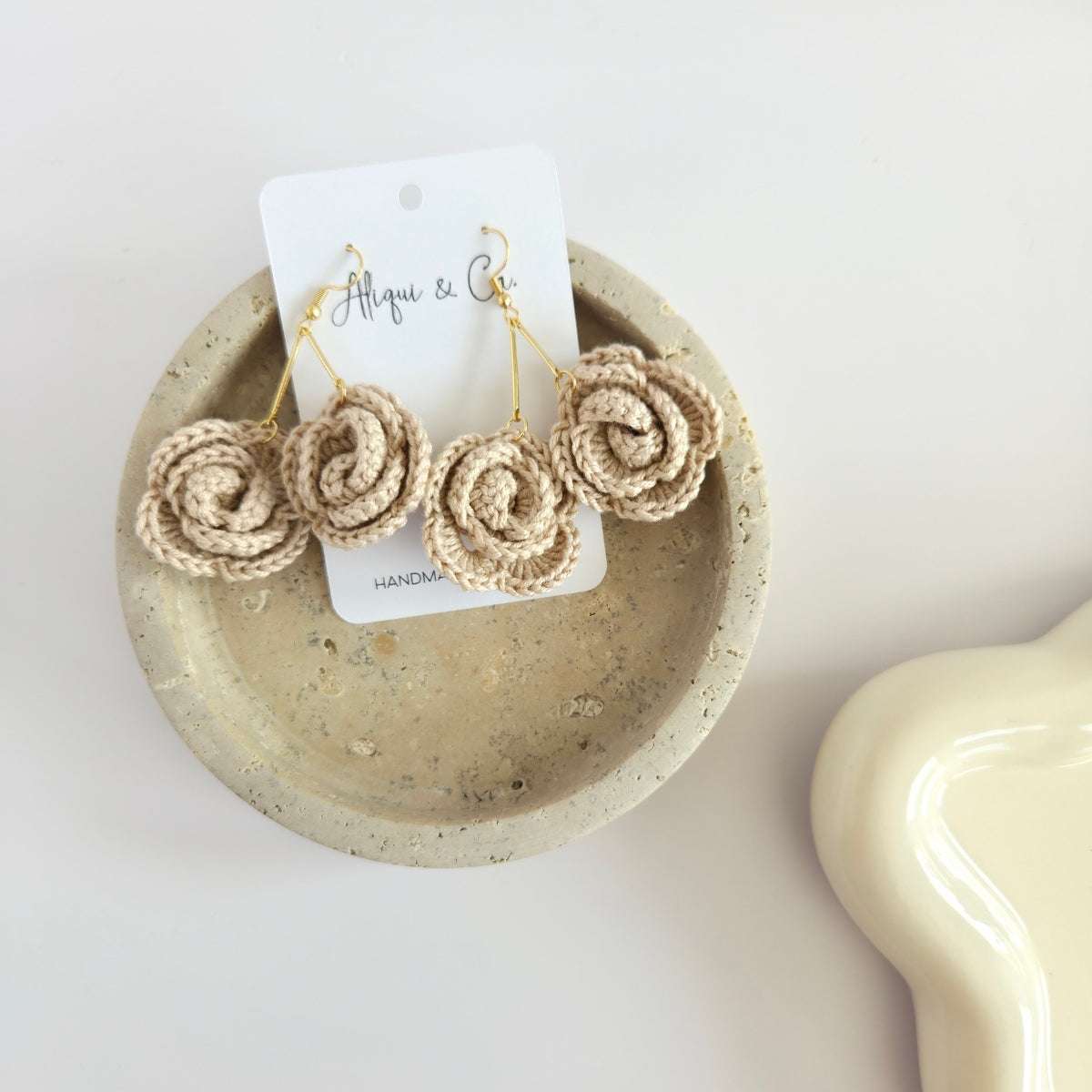 Pair of light tan rose floral earrings on a white background with a 'Alqui & Co' tag.