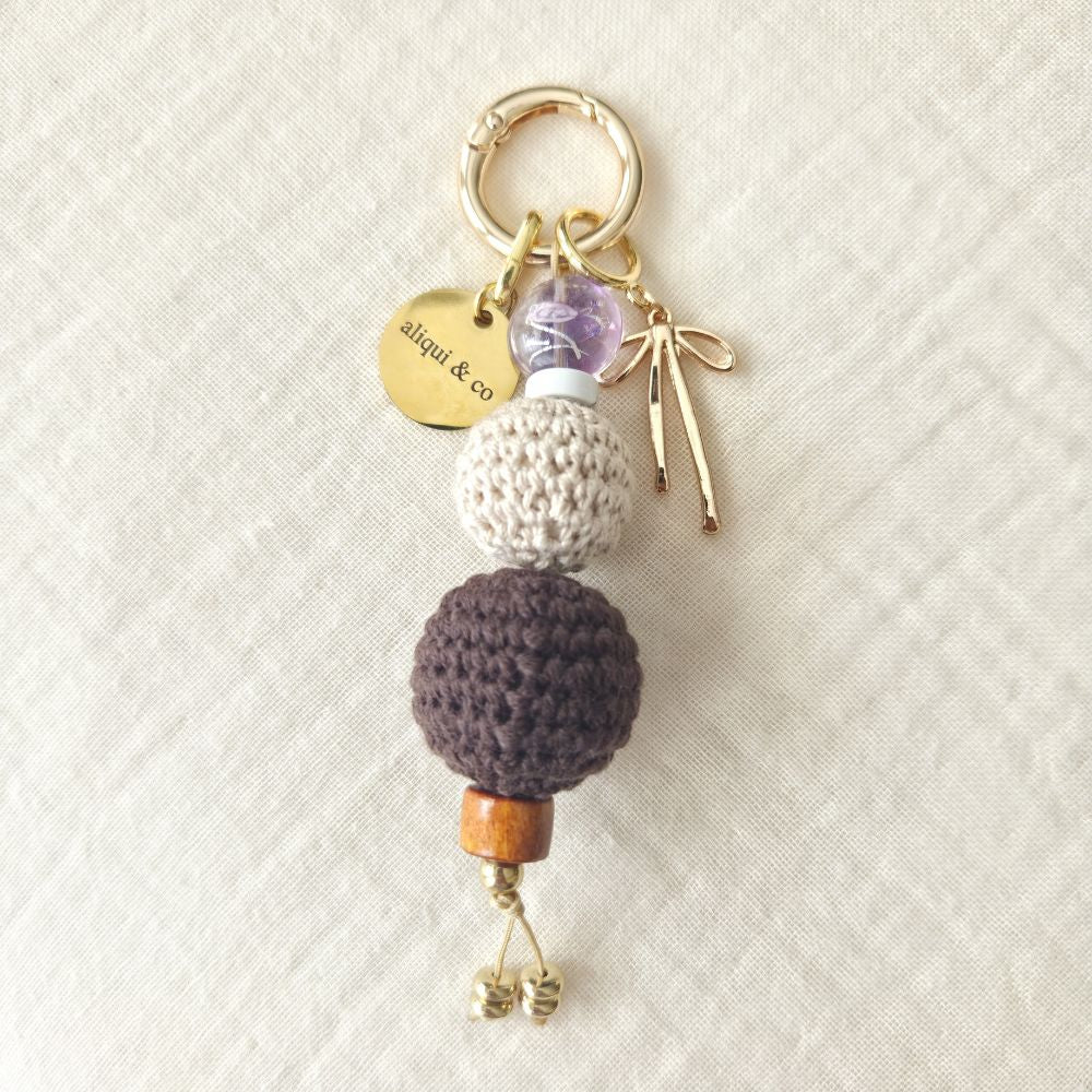 Keychain with crocheted beads and charms on a textured beige background