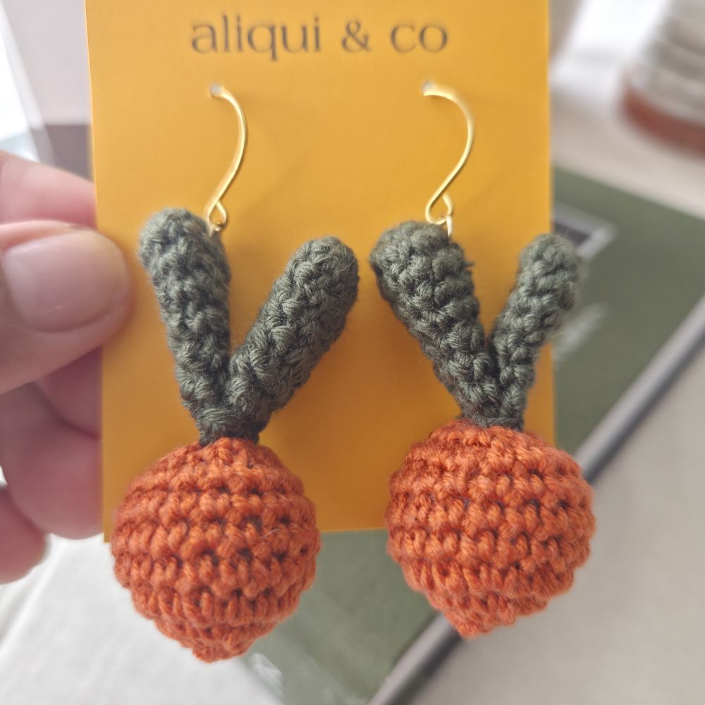 Crocheted earrings with orange and green balls on a 'alliqui & co' card.