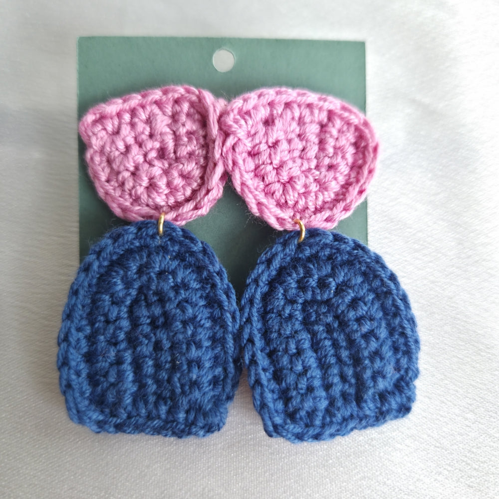 Pair of crocheted earrings with pink and blue half circular patterns on a white background.