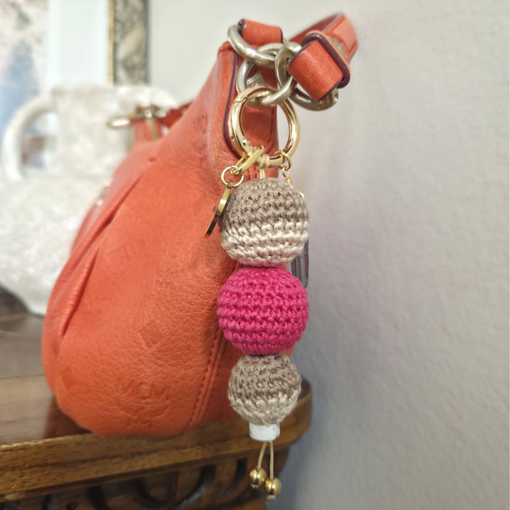 Keychain with beads attached to an orange handbag on a wooden surface.