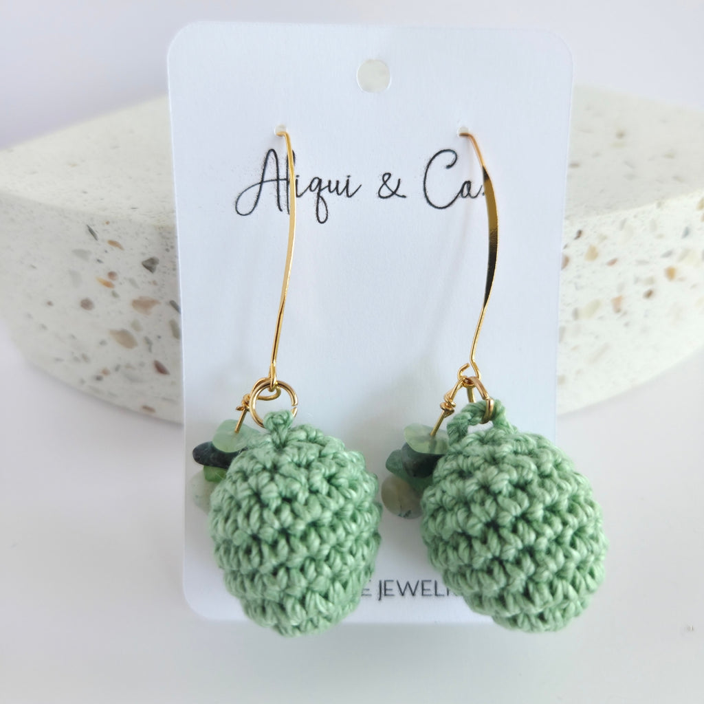 Green handmade crocheted earrings on a white card with 'Alqui & Co' branding.