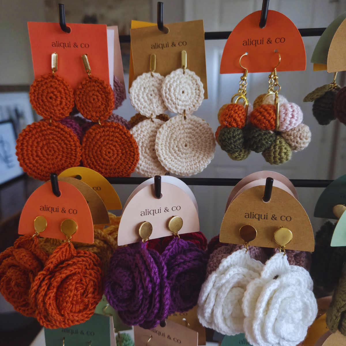 Assorted handmade crochet earrings on display with 'aliqui & co' tags.