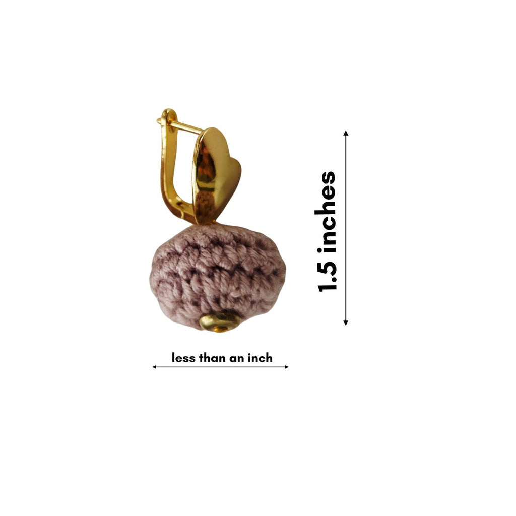 A single gold-toned earring with a textured mauve-pink crocheted pom-pom charm, shown with dimension arrows and text indicating a height of 1.5 inches and a width of less than an inch, on a plain white background.