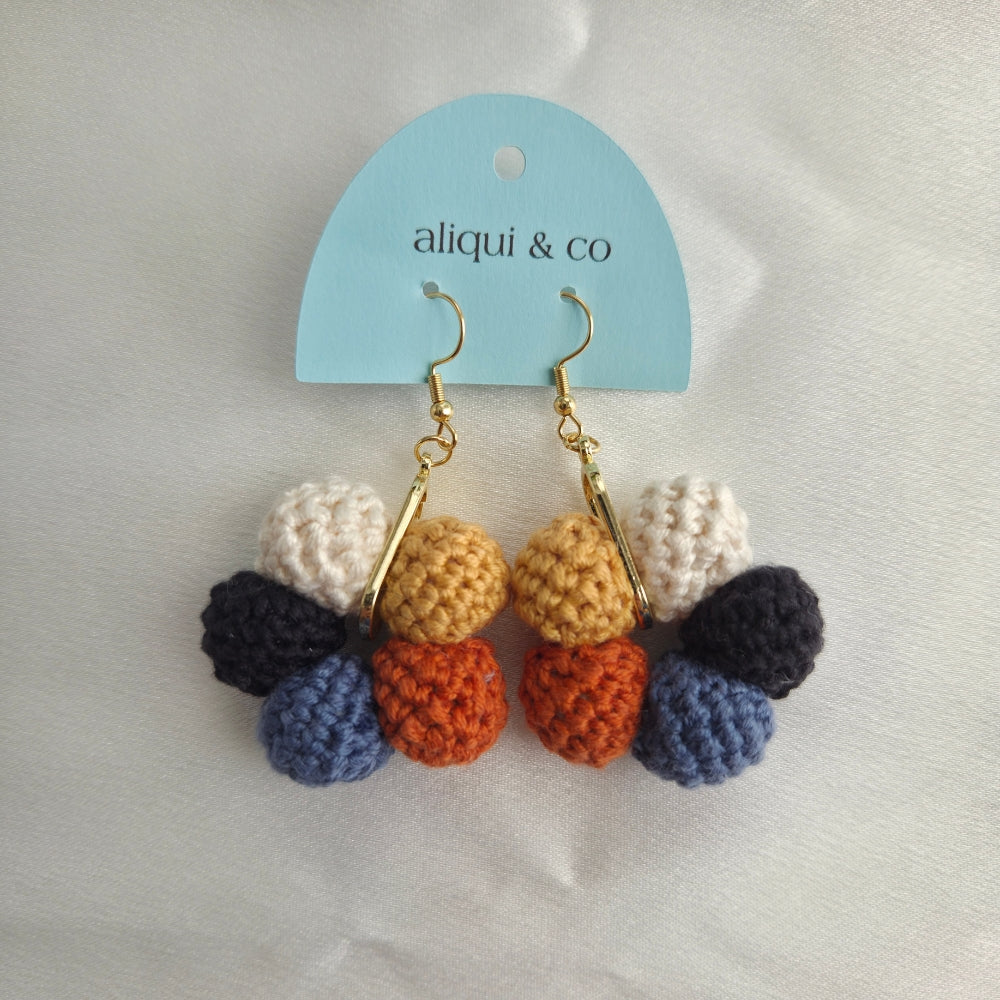 Colorful crocheted earrings on a 'aliqui & co' branded card against a light background