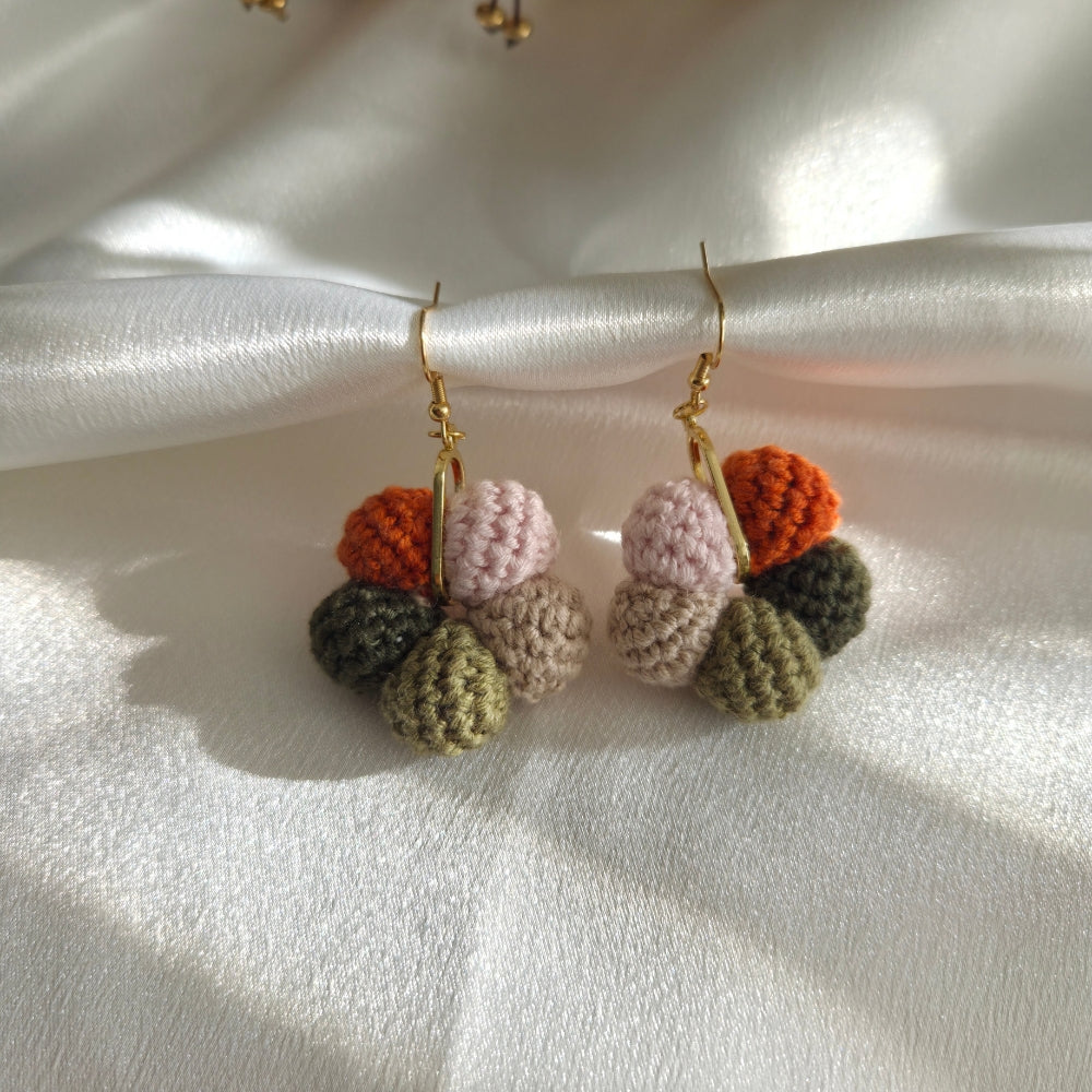 Colorful crocheted earrings on a white satin background