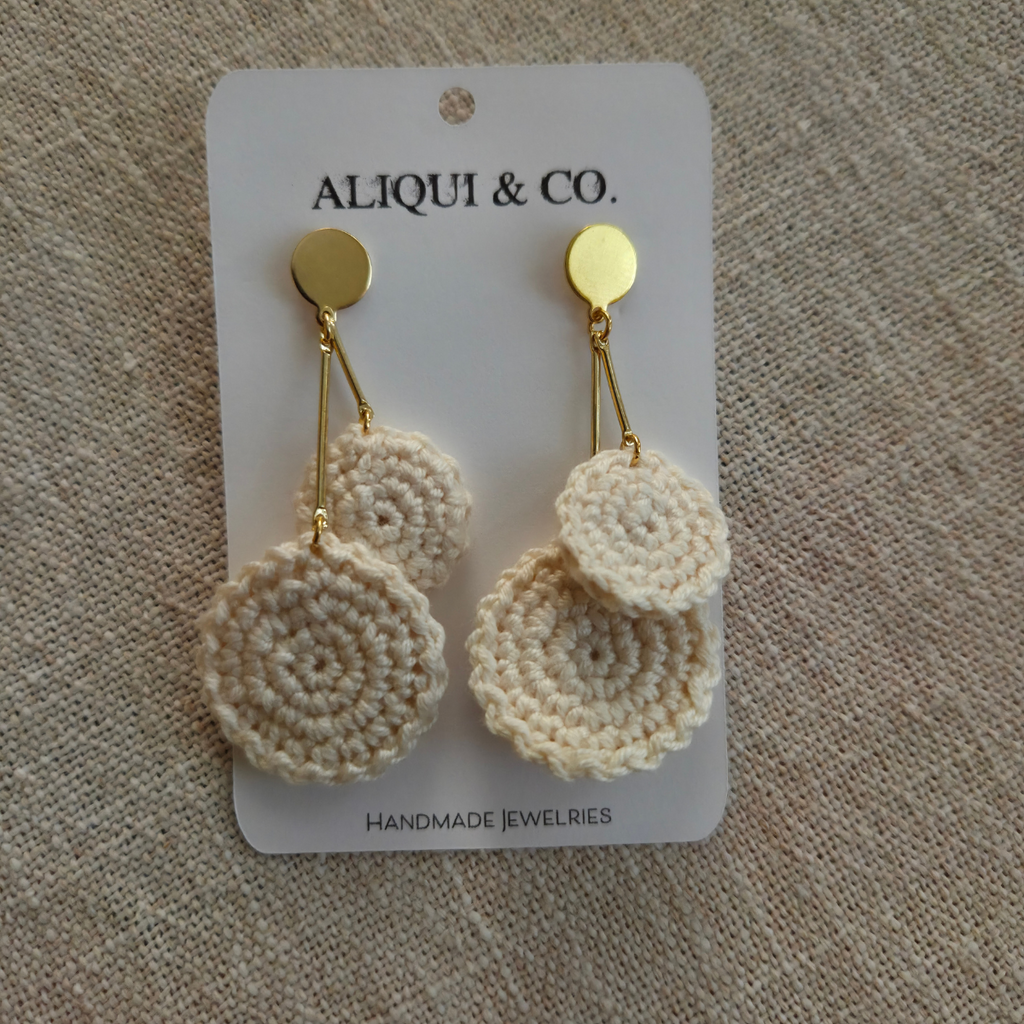 Cream crocheted earrings on a Aliqui & Co card against a textured beige background