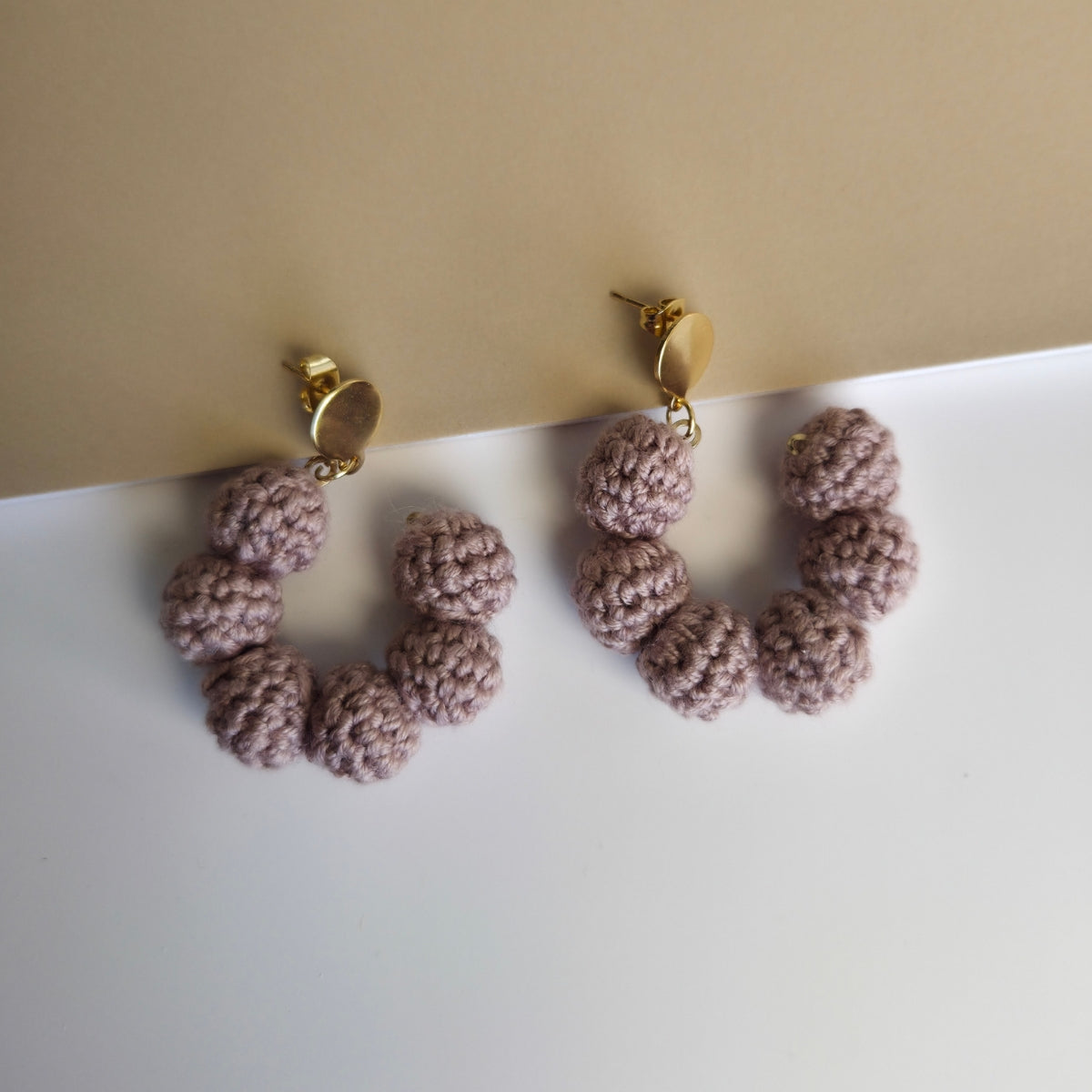 Pair of pink knitted earrings on a beige background