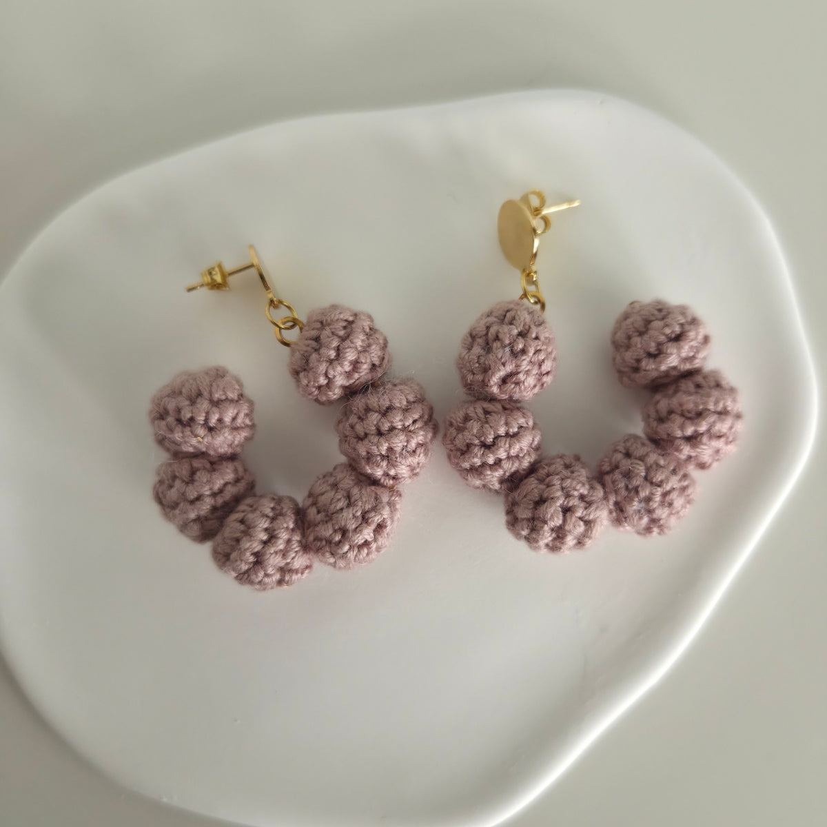 Pair of pink crochet earrings on a white heart-shaped plate