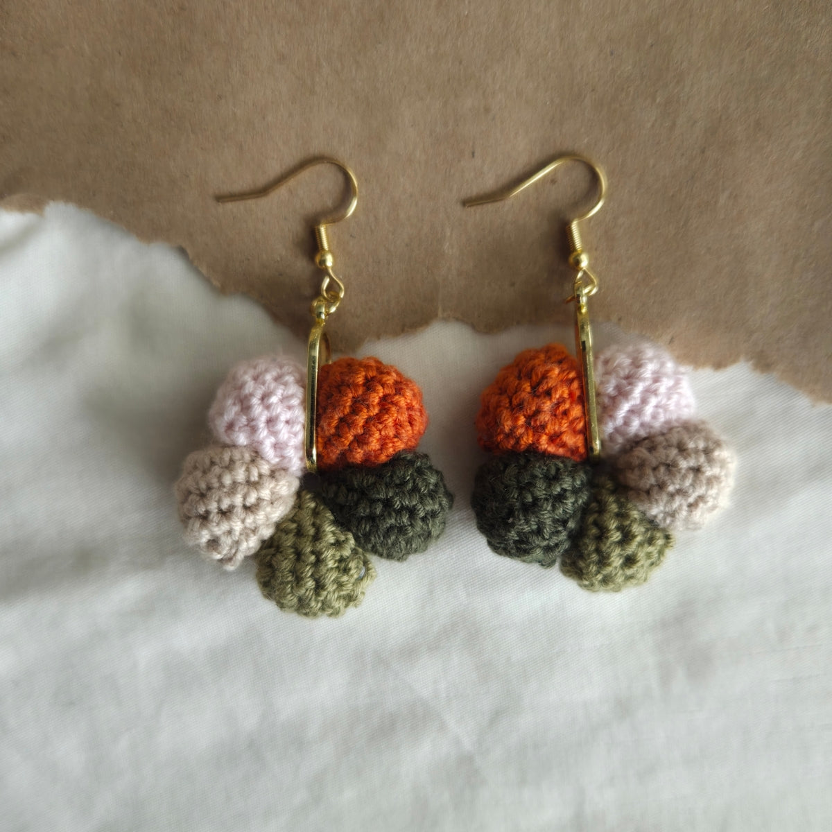 Crocheted multicolored sphere earrings on a white surface with a brown background