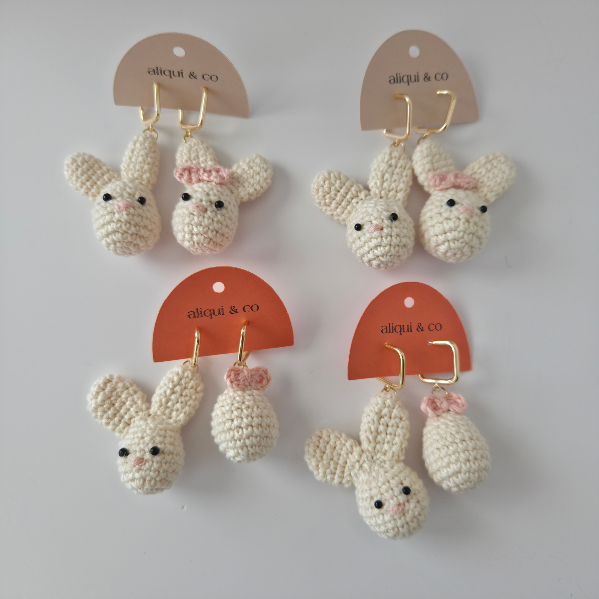 Set of crocheted bunny earrings with pink bows on a white background with 'aliqui & co' tags.