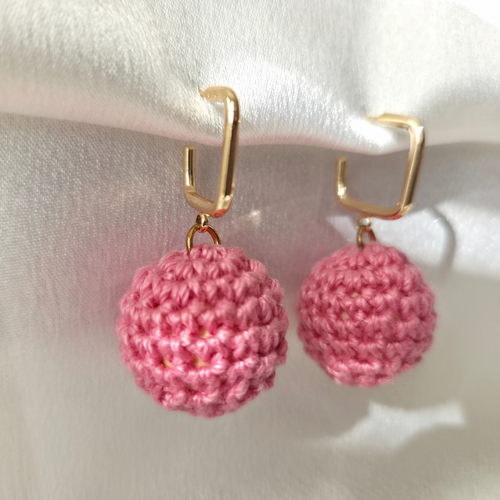 Pink crochet earrings with gold hooks on a white background