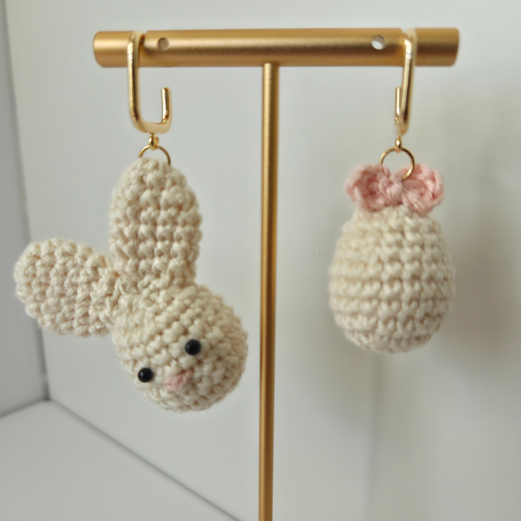 Crocheted bunny and Easter eggs on a gold stand against a white background