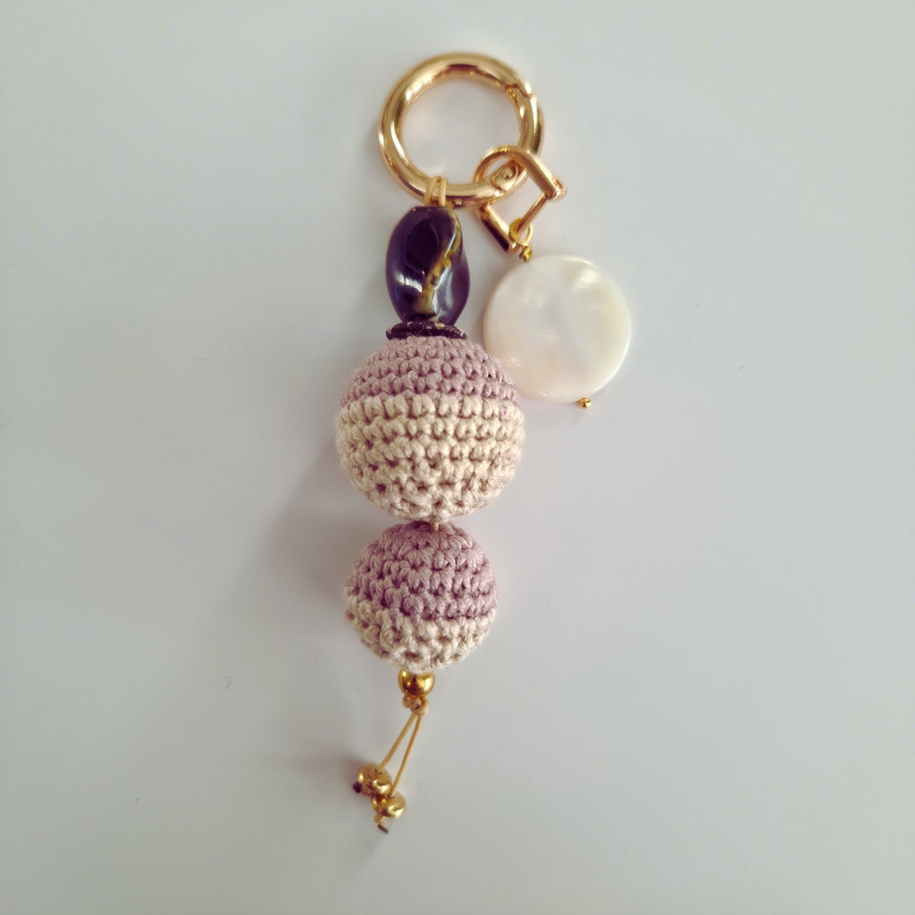 Keychain with crocheted balls and a pearl on a light pink and cream background