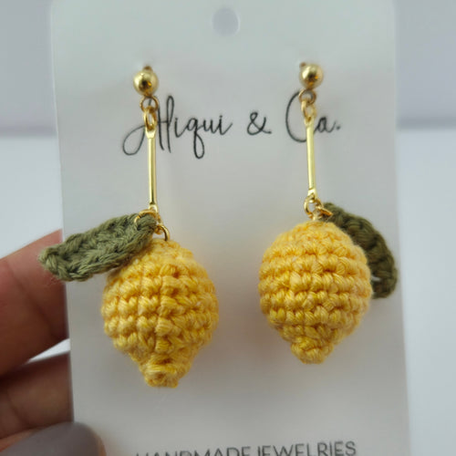 Yellow crochet earrings on a branded card held by a hand.