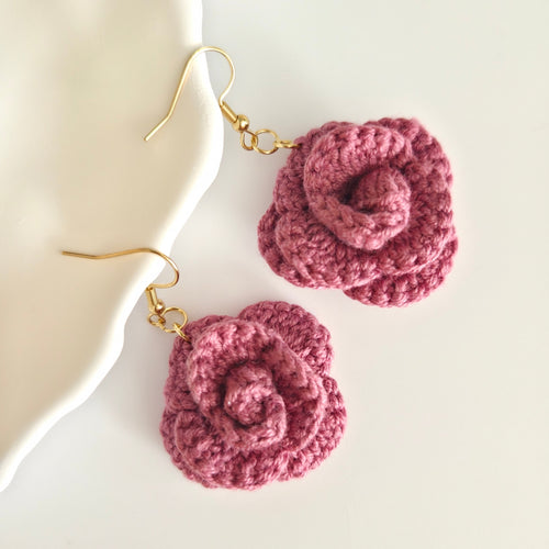 A pink crochet rose earrings on a white background