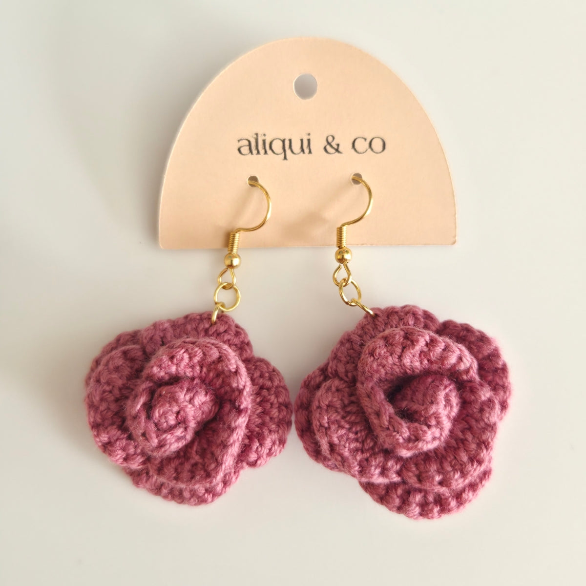 A pink rose earring on a brand 'aliqui & co'  card
