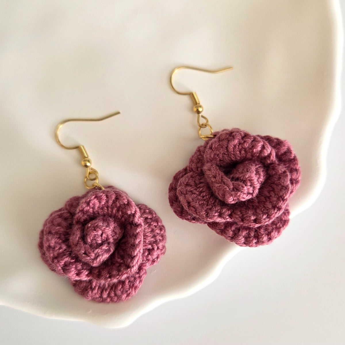 Crochet rose earring on a white plate background
