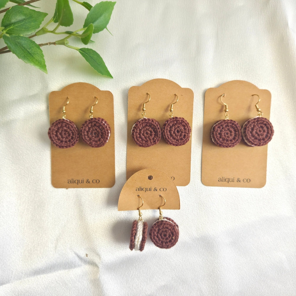 Three pairs of earrings on aliqui & co cards against a white background with green leaves.