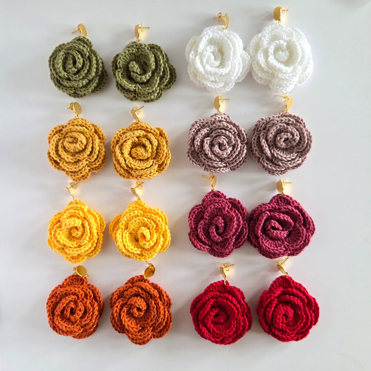 Set of crocheted rose earrings in various colors on a white background
