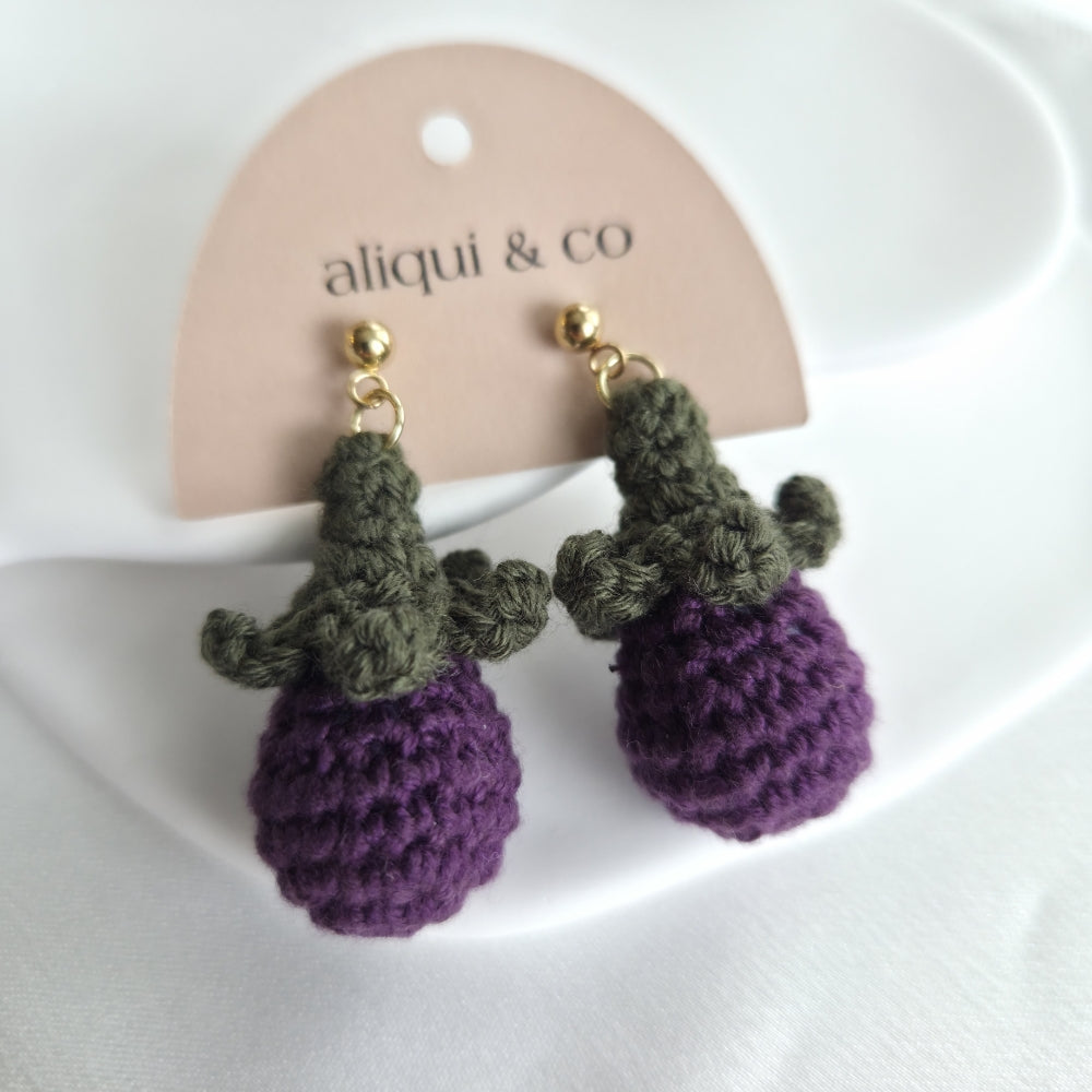 Crocheted earrings shaped like purple fruits on a 'aliqui & co' branded card.