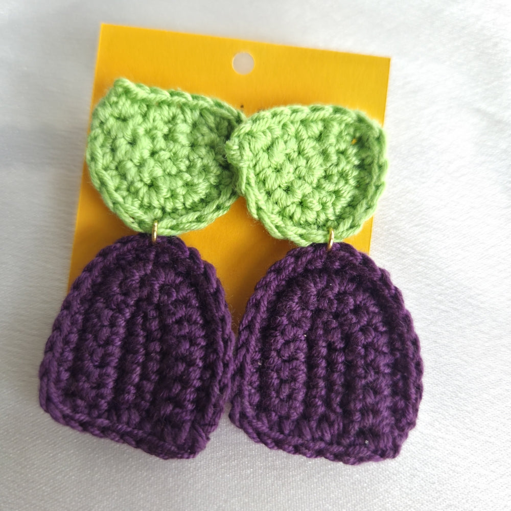 Beautiful minimalist crocheted earrings with green leaves on a yellow card against a white background