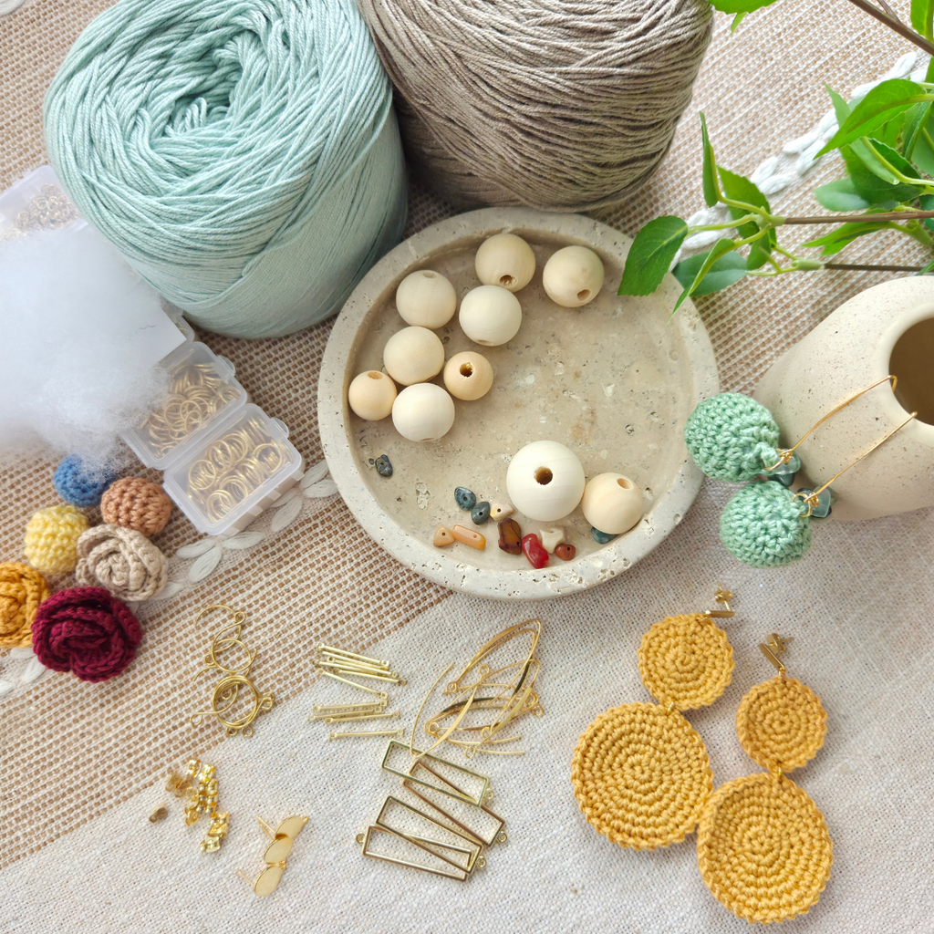 High quality materials for making earrings including yarn, beads, and crochet items on a textured surface.