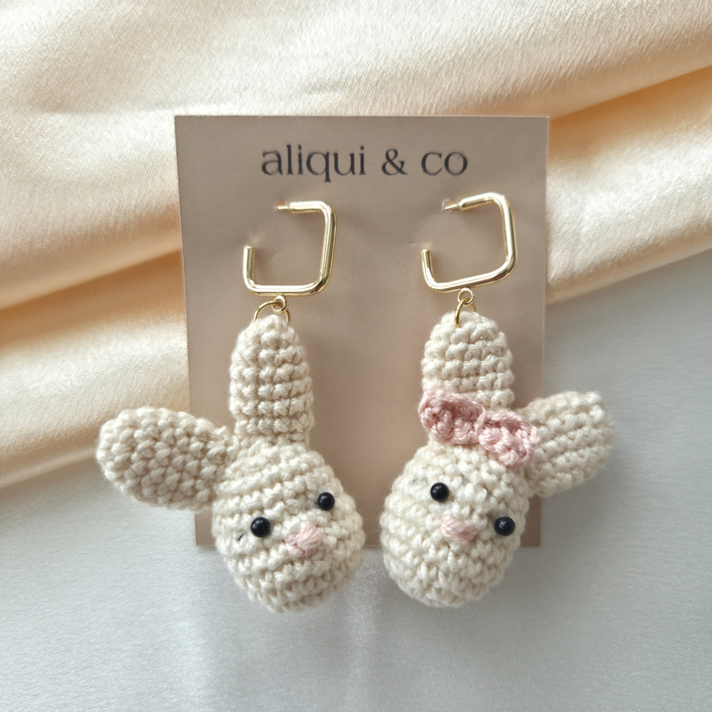 Pair of crocheted bunny earrings with a pink bow on a 'aliqui & co' card.