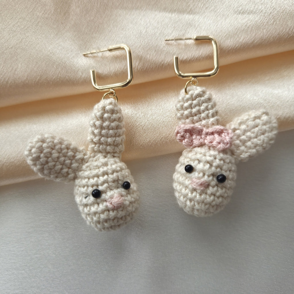 Pair of easter crochet bunny earrings with a bow on a light background