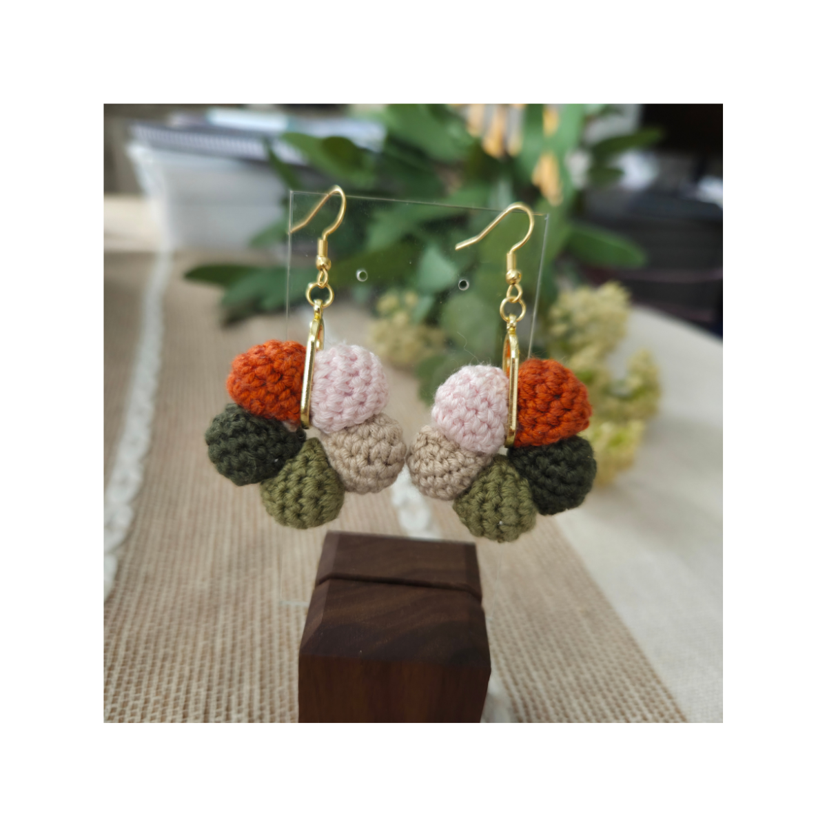 Colorful crochet earrings on a wooden block with a blurred background