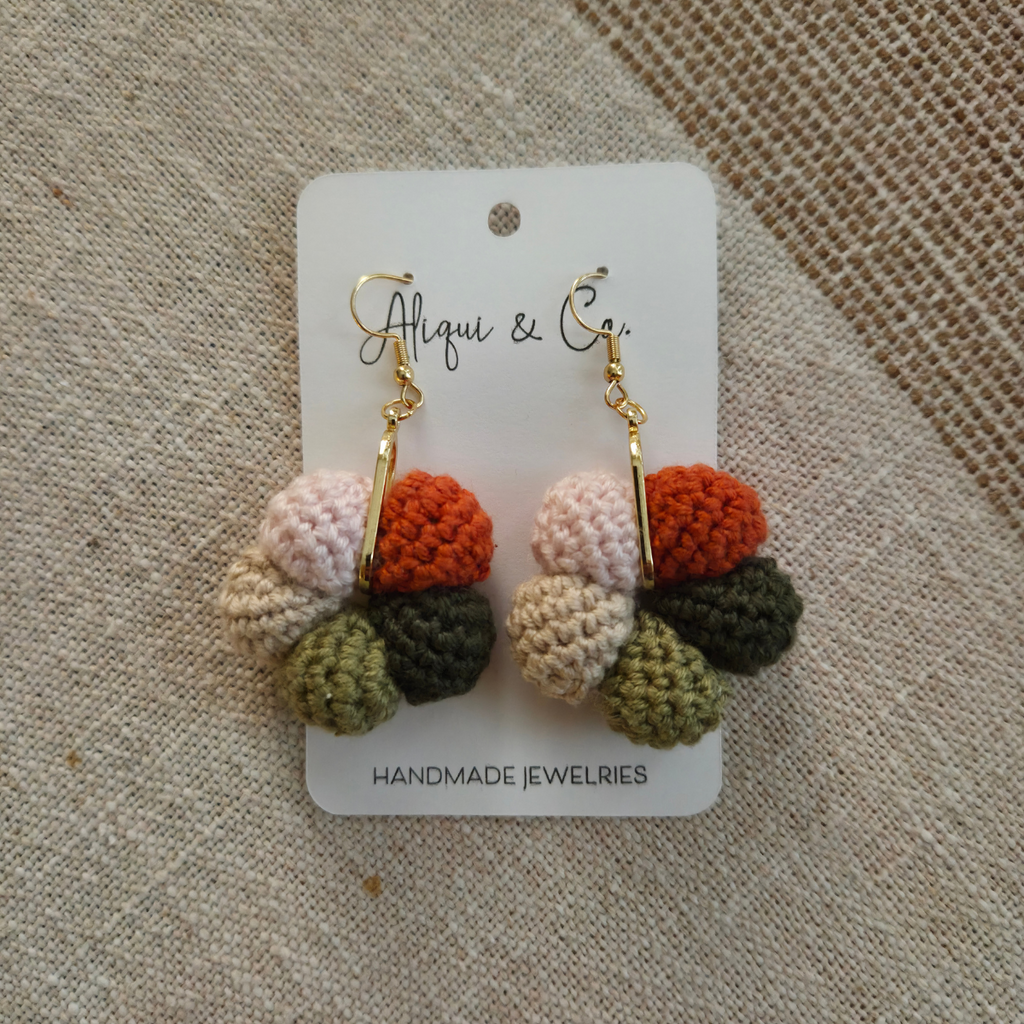 Handmade crocheted earrings on a card with 'Aliqui & Co' branding on a textured fabric background