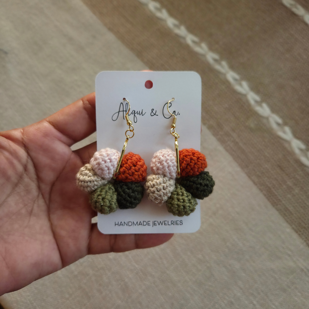Handmade earrings on a card held by a hand, with a neutral background