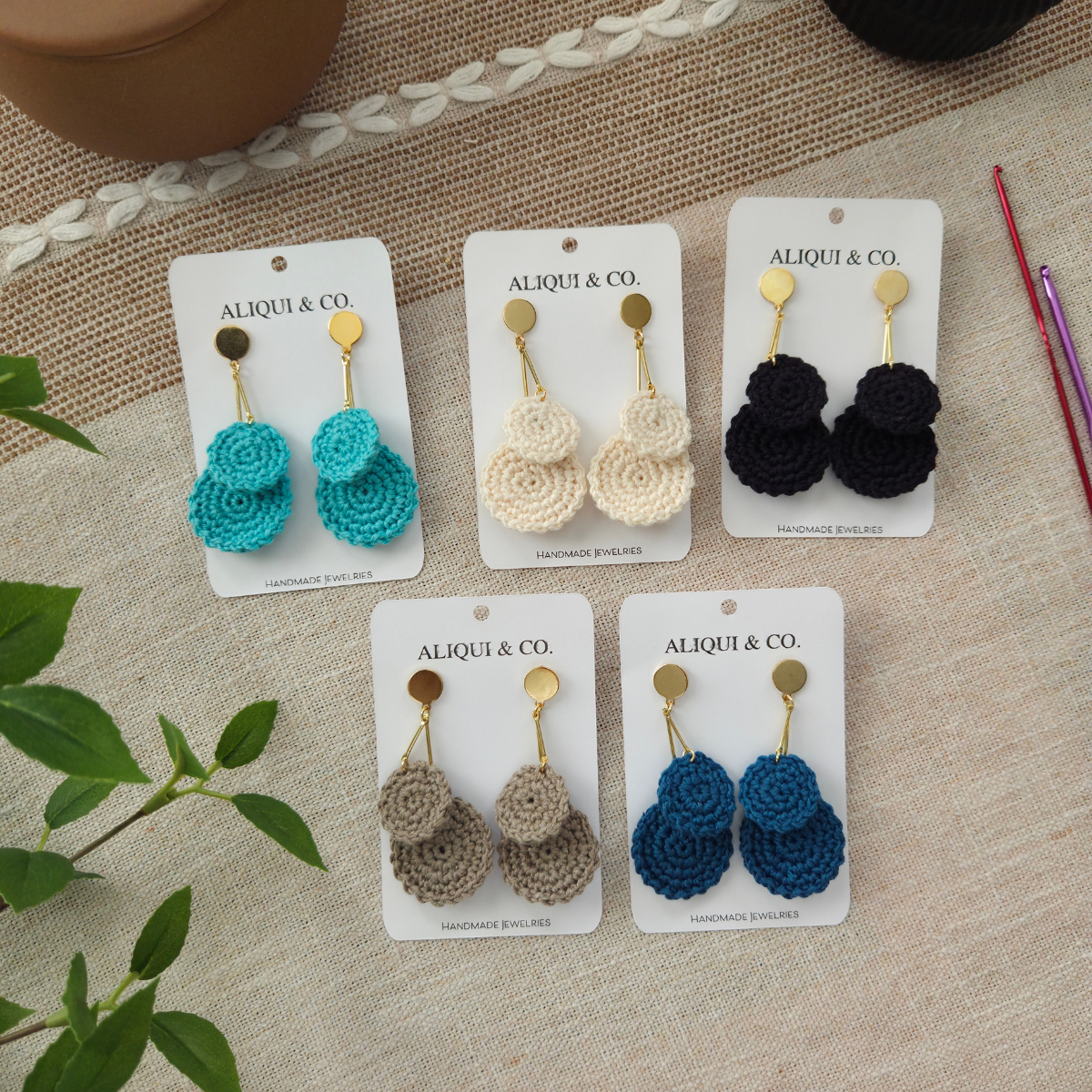 Five sets of crochet drop earrings on a textured background