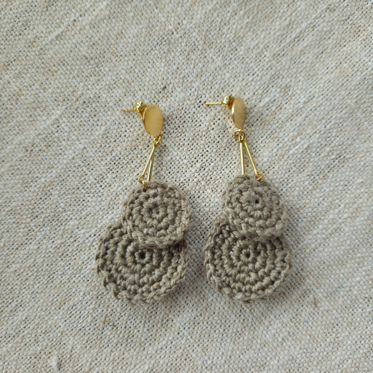 Pair of oak crochet earrings on a textured fabric background