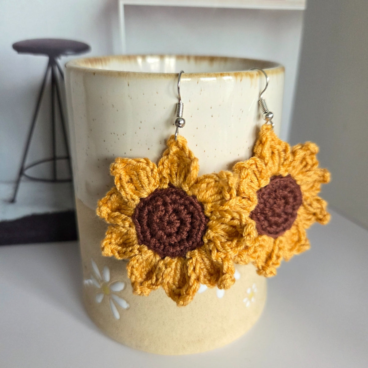 Crocheted sunflower earrings displayed in a ceramic vase