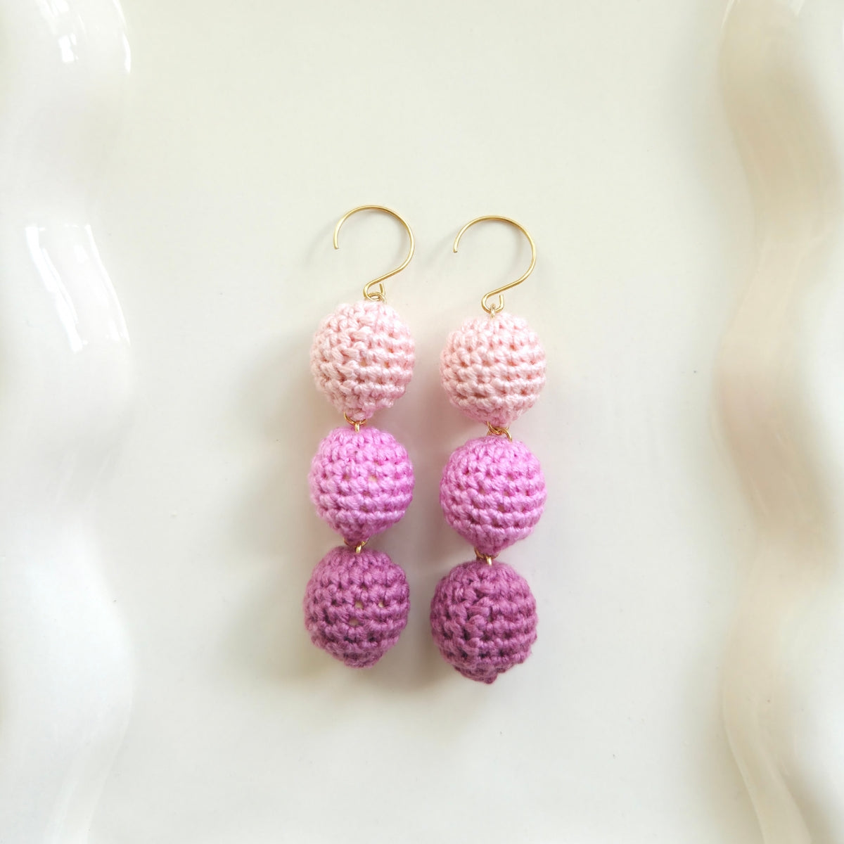 Pink tri-crochet ball earrings on a white background