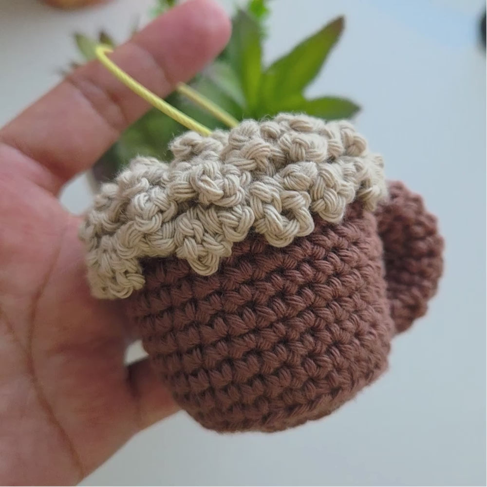 a video of a hand holding a crochet beer mug on a foamy top.