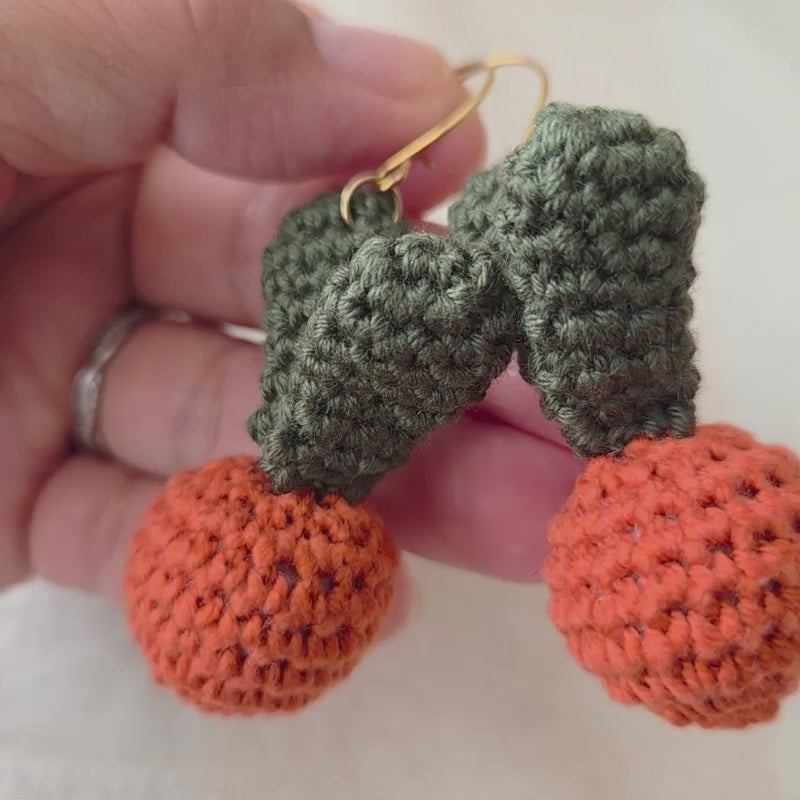 A video of a crochet carrot earrings in a golden  hook