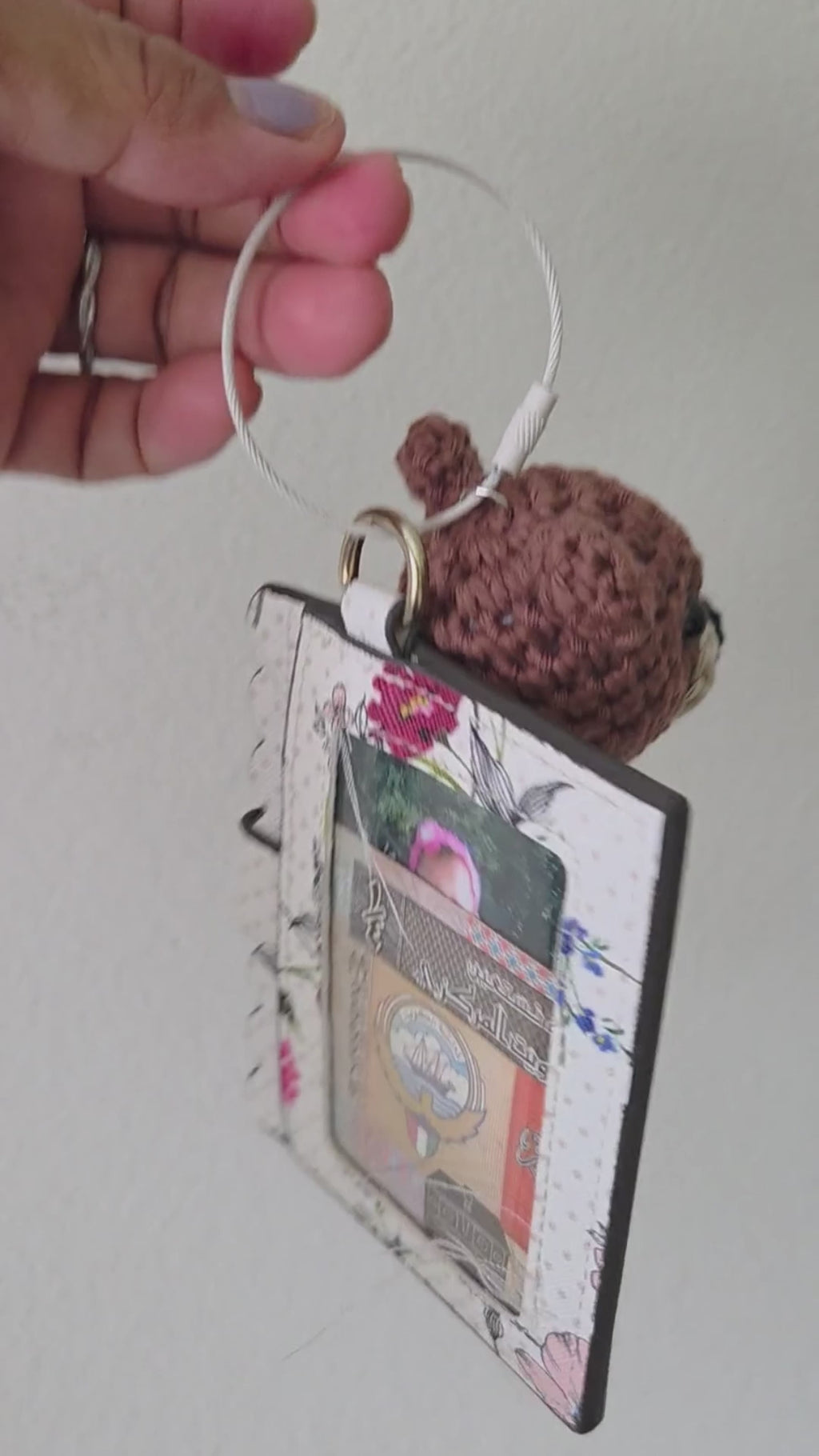 A video of an amigurumi crochet bear in brown with white metal keyring and  a small card holder