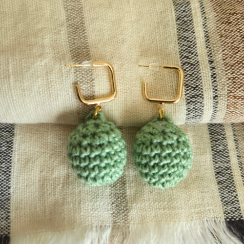 Sage  crochet earrings on a textured fabric background